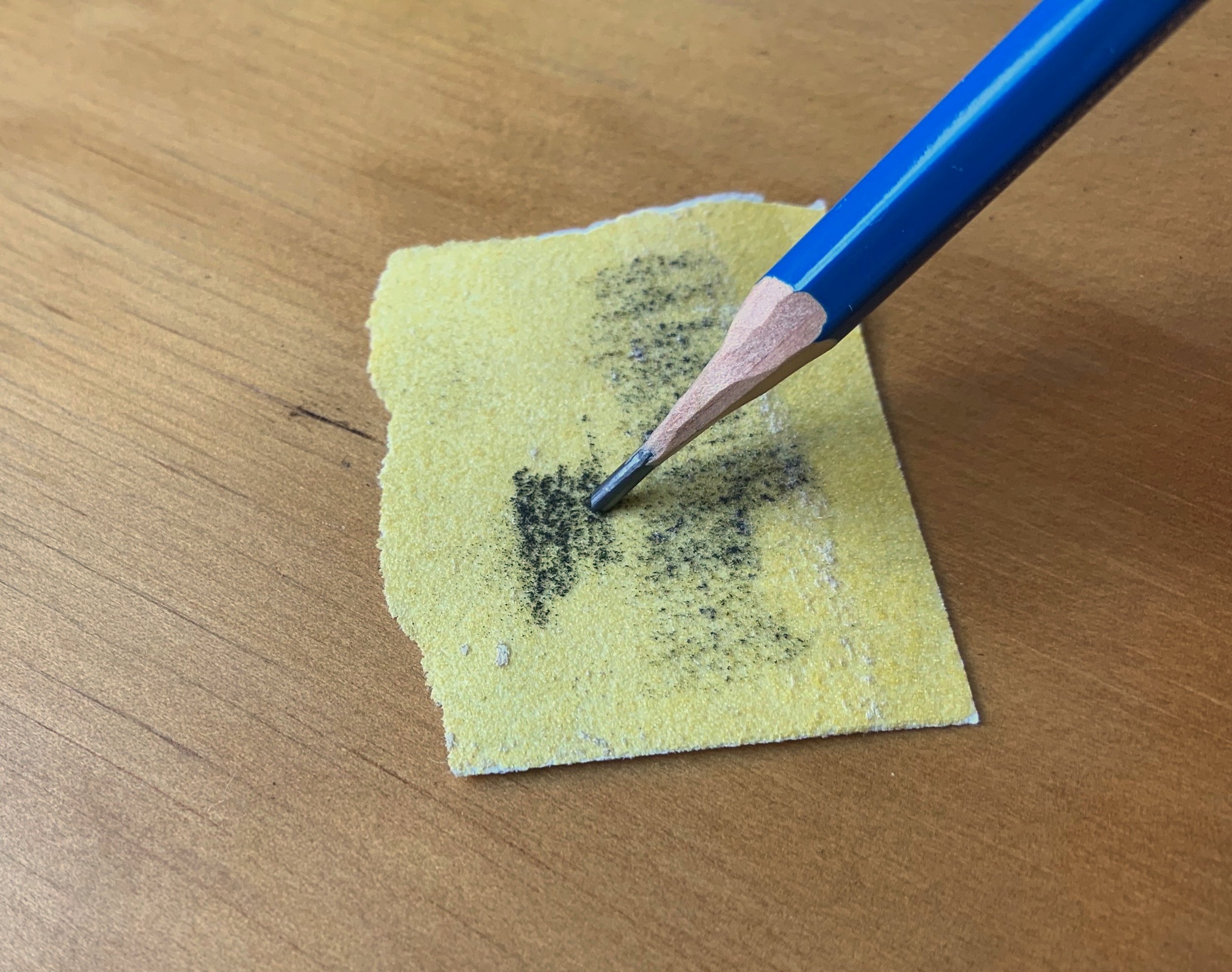 The lead of the pencil is filed on sandpaper to form a flat wedge